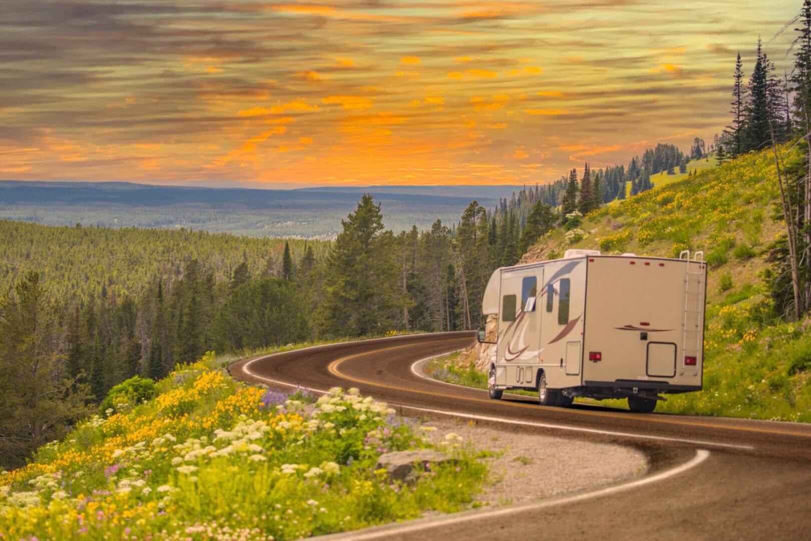 RV driving on scenic mountain road at sunset.