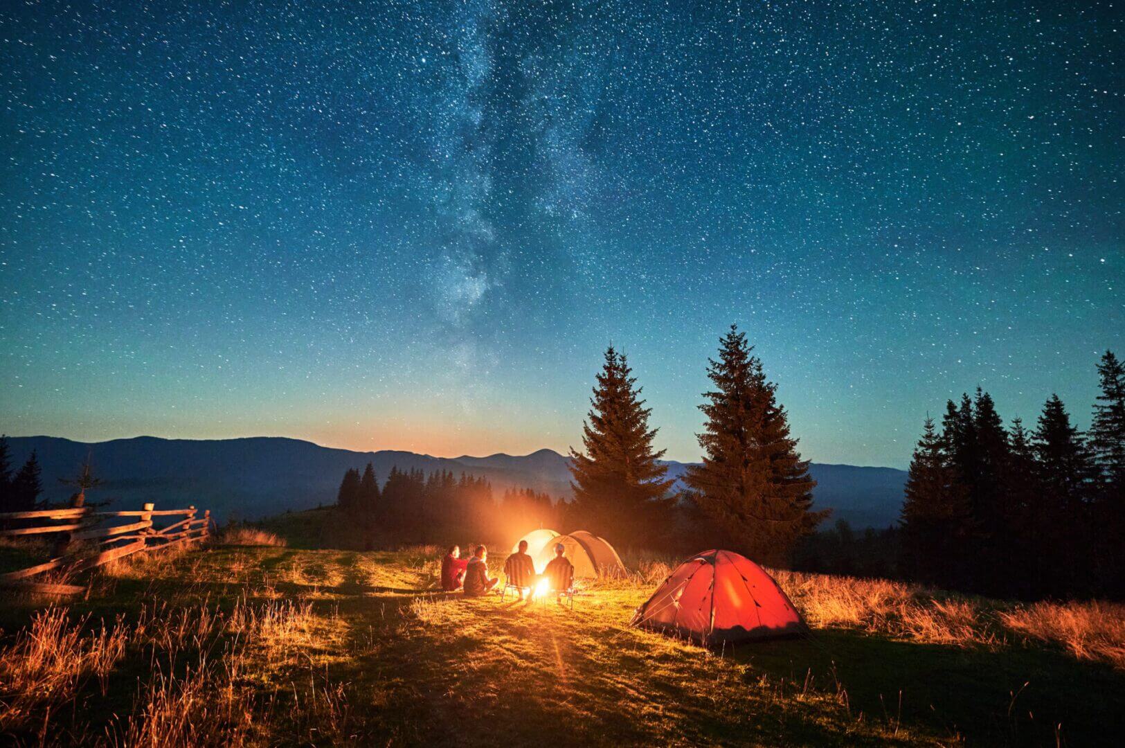 Camping under starry sky with campfire.