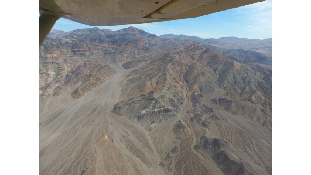 Aerial view of a rugged, mountainous desert landscape under a clear sky.