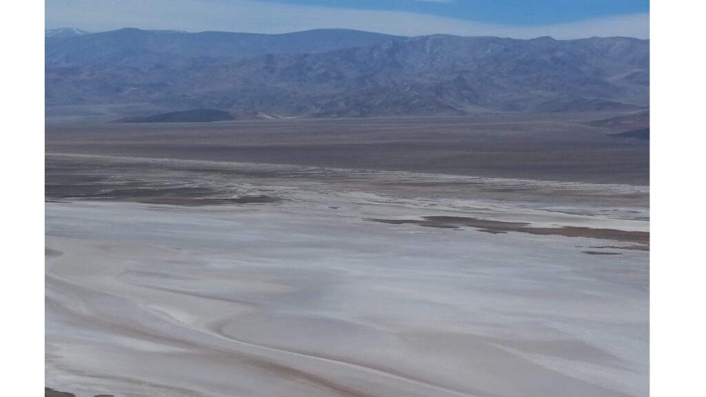 Vast dry salt flats with distant mountain range under a clear sky.