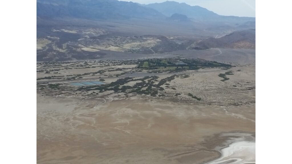Aerial view of a dry, mountainous landscape with sparse vegetation.