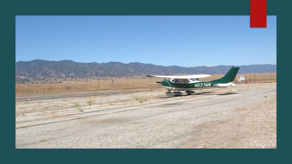 Man standing next to a small private airplane on a cloudy day.